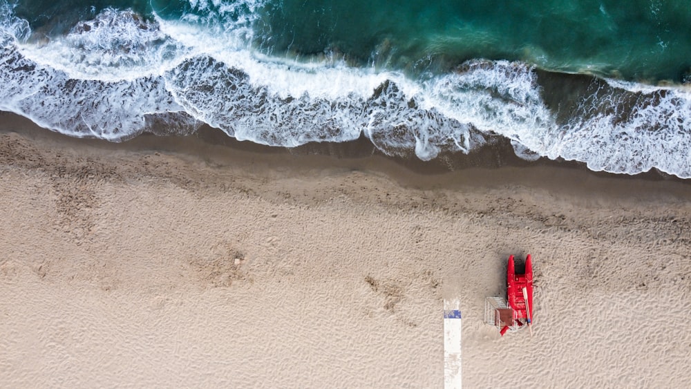 an aerial view of a red boat on the beach