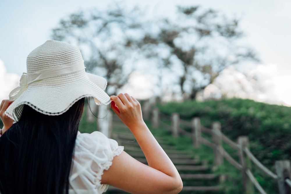a woman in a white hat walking up a set of stairs