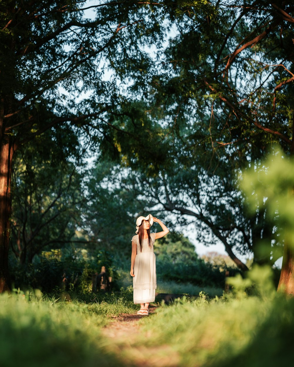 a woman in a white dress walking through a forest