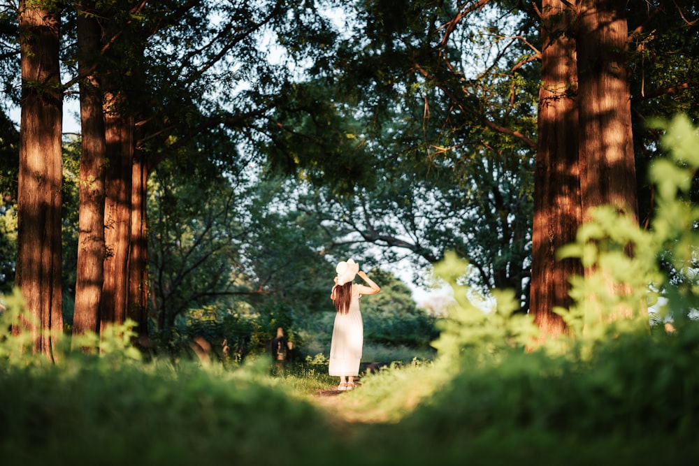 森の中に立つ白いドレスを着た女性