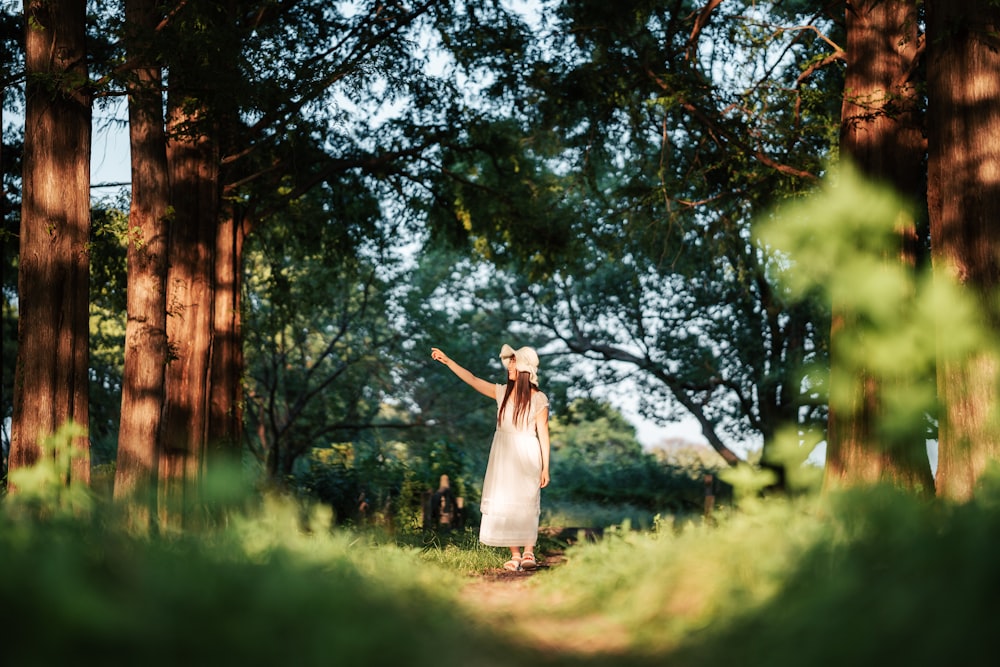 a woman in a white dress standing in a forest