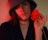 a woman in a hat holding a red flower