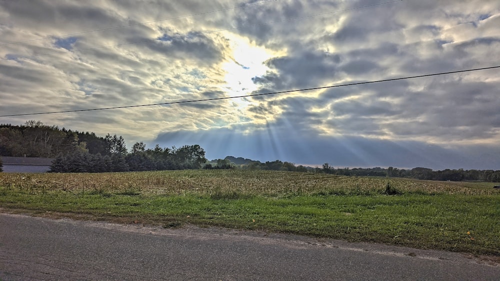 the sun is shining through the clouds over a field