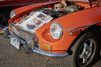 an orange car with a newspaper on the hood