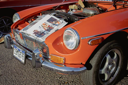 an orange car with a newspaper on the hood