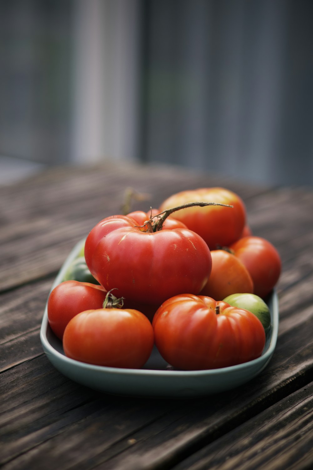 um prato de tomates em uma mesa de madeira