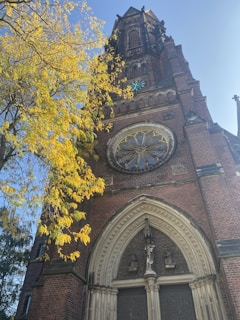 Ancient church facade with intricate stone carvings surrounded by autumn foliage.