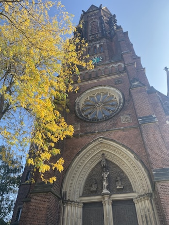 Ancient church facade with intricate stone carvings surrounded by autumn foliage.