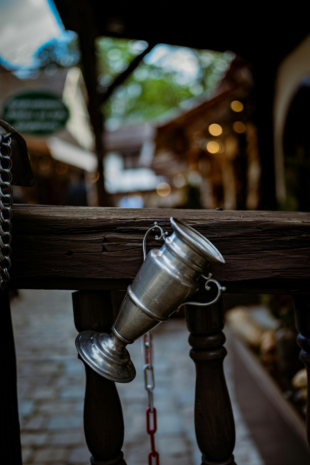 a metal cup hanging from a wooden rail