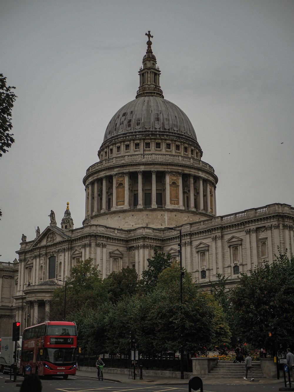 a red double decker bus driving past a large building