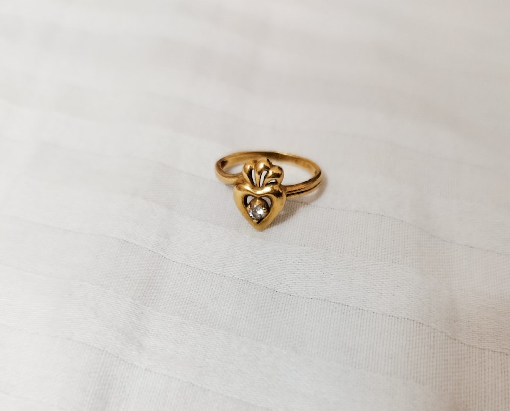 um close up de um anel de ouro em uma superfície branca