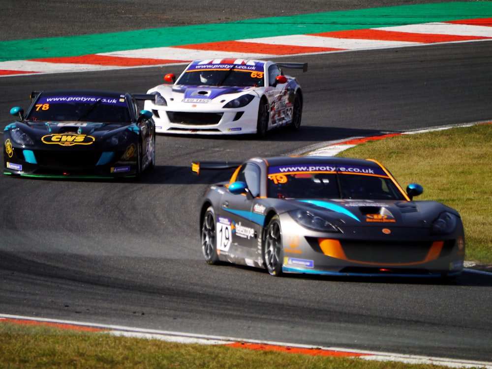 três carros de corrida correndo em uma pista de corrida