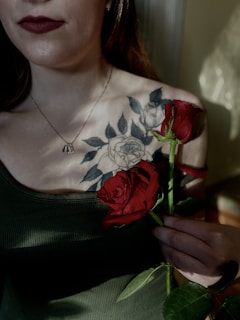 Tattoo of a realistic rose with delicate petals and shadows, inked on the shoulder.
