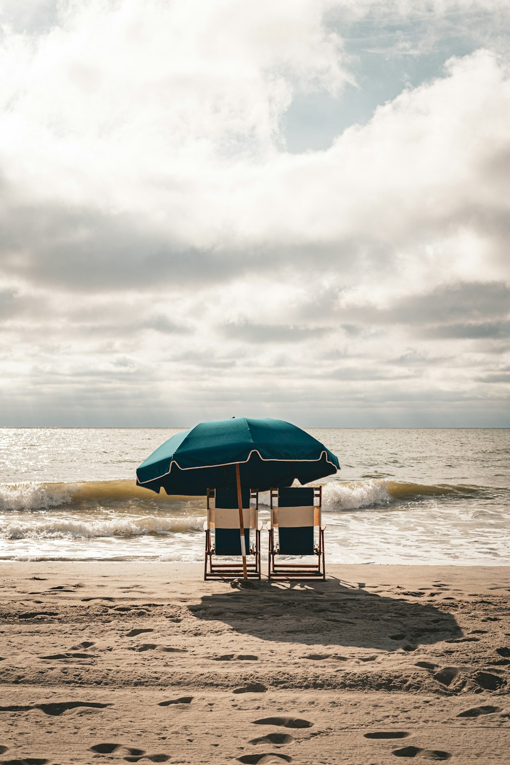 a couple of chairs sitting under an umbrella on a beach