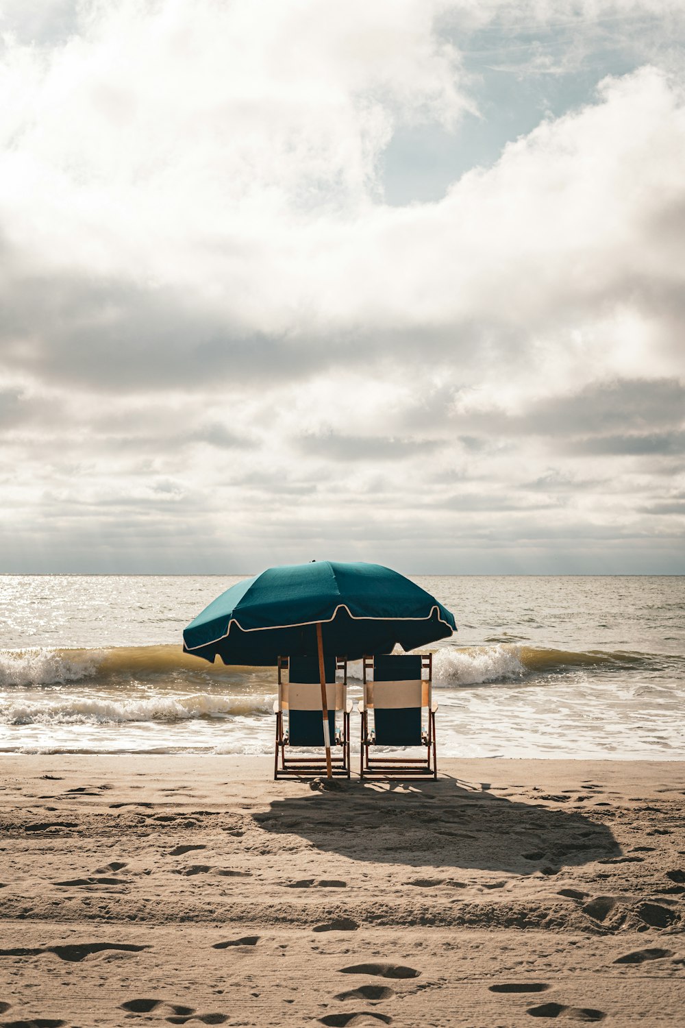 Un par de sillas sentadas bajo una sombrilla en una playa