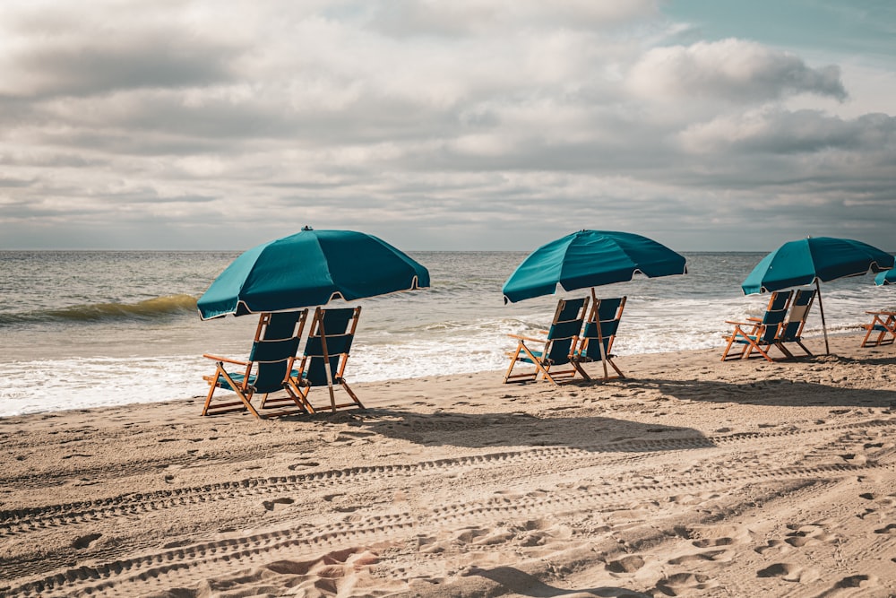 a couple of lawn chairs sitting on top of a sandy beach