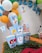 A festive party setup featuring colorful balloons in the background. Brightly colored popcorn boxes showcase cartoon characters, including a rabbit with a carrot and other well-known animated figures. The table is adorned with a green leafy runner and additional decorations such as a tooth-shaped figure and a bowl of candy.