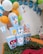 A festive party setup featuring colorful balloons in the background. Brightly colored popcorn boxes showcase cartoon characters, including a rabbit with a carrot and other well-known animated figures. The table is adorned with a green leafy runner and additional decorations such as a tooth-shaped figure and a bowl of candy.