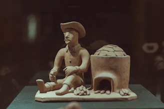 Traditional clay sculpture of a man wearing a hat and carrying a bag, symbolizing local heritage.
