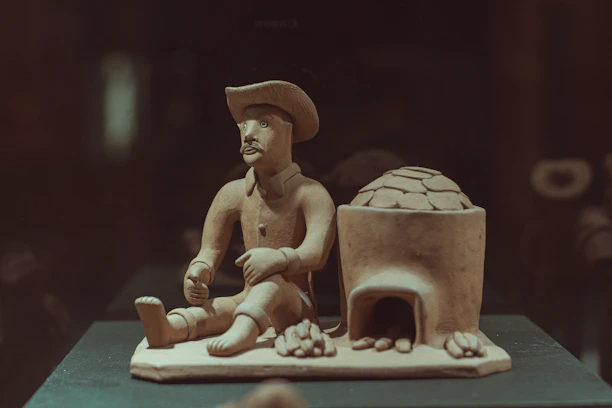 Traditional clay sculpture of a man wearing a hat and carrying a bag, symbolizing local heritage.