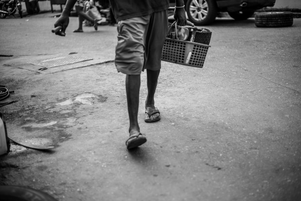 a man walking down a street carrying a basket