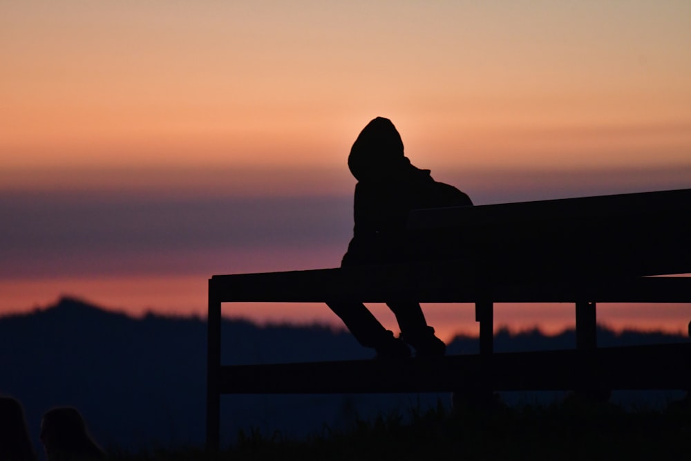 a silhouette of a person sitting on a bench