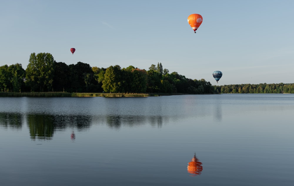 several hot air balloons flying over a lake
