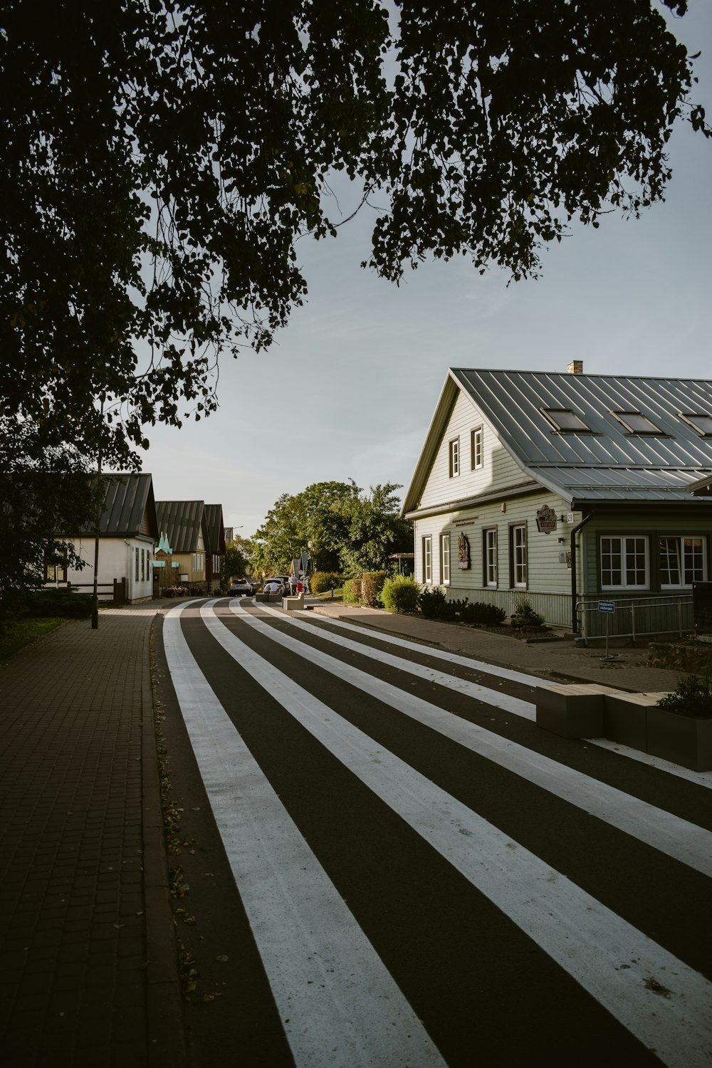 a white house with a black roof next to a tree