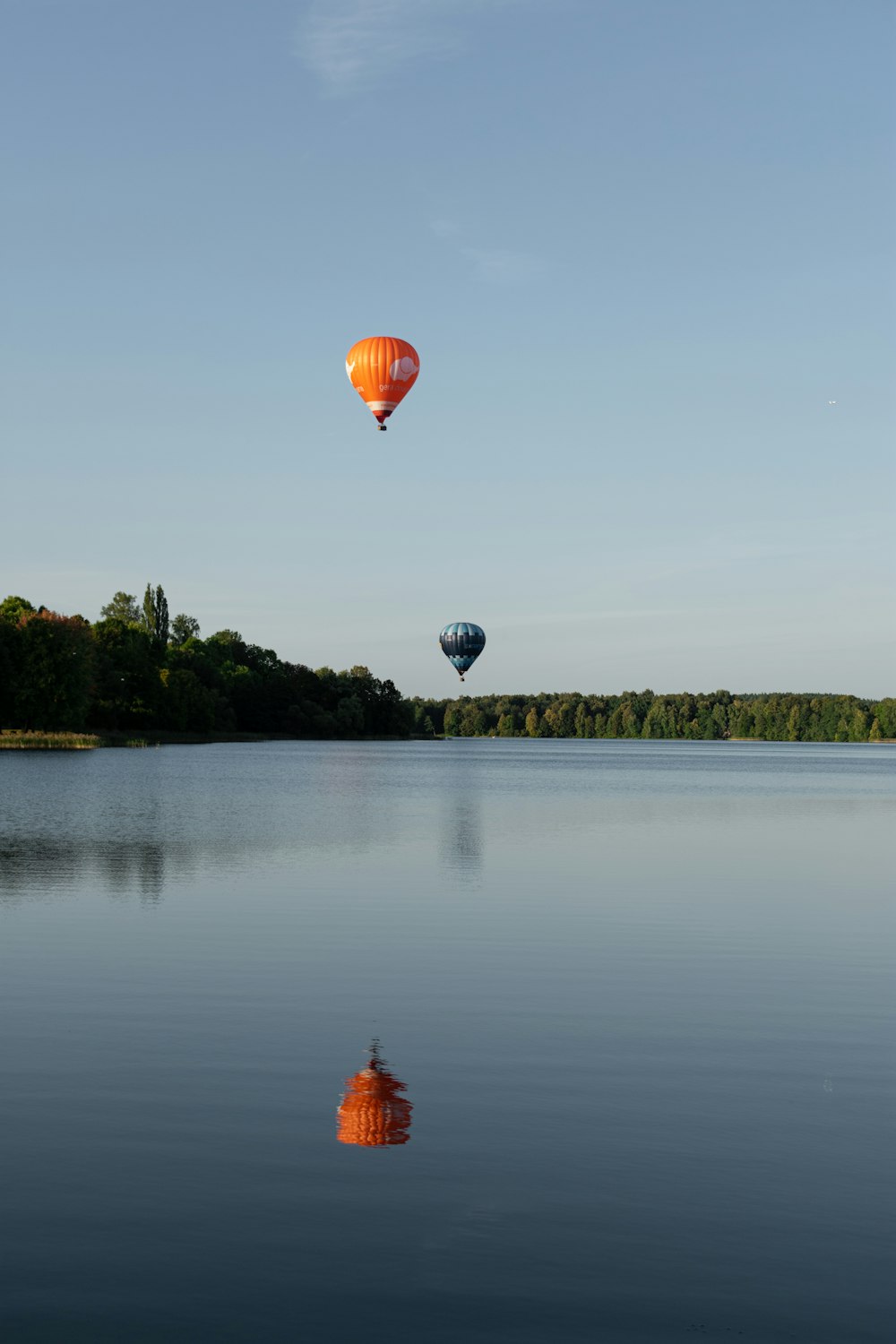 two hot air balloons flying over a lake