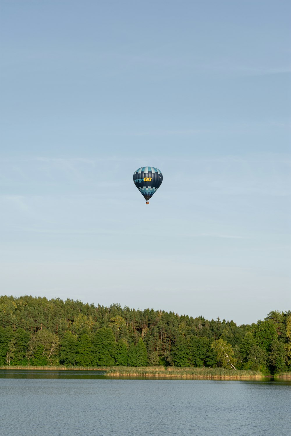 a hot air balloon flying over a lake