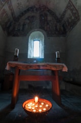 A peaceful chapel interior with candles glowing gently around an altar.