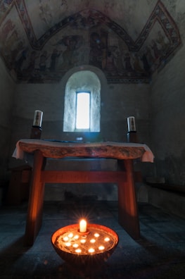 Soft candlelight flickering beside a simple chalice on an altar.