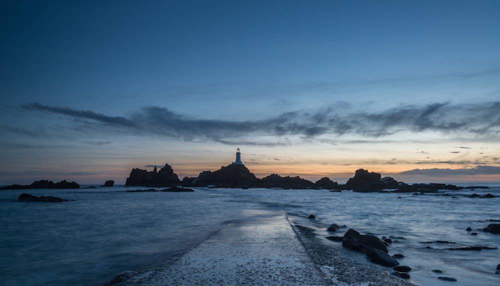 a lighthouse on a rocky shore at sunset