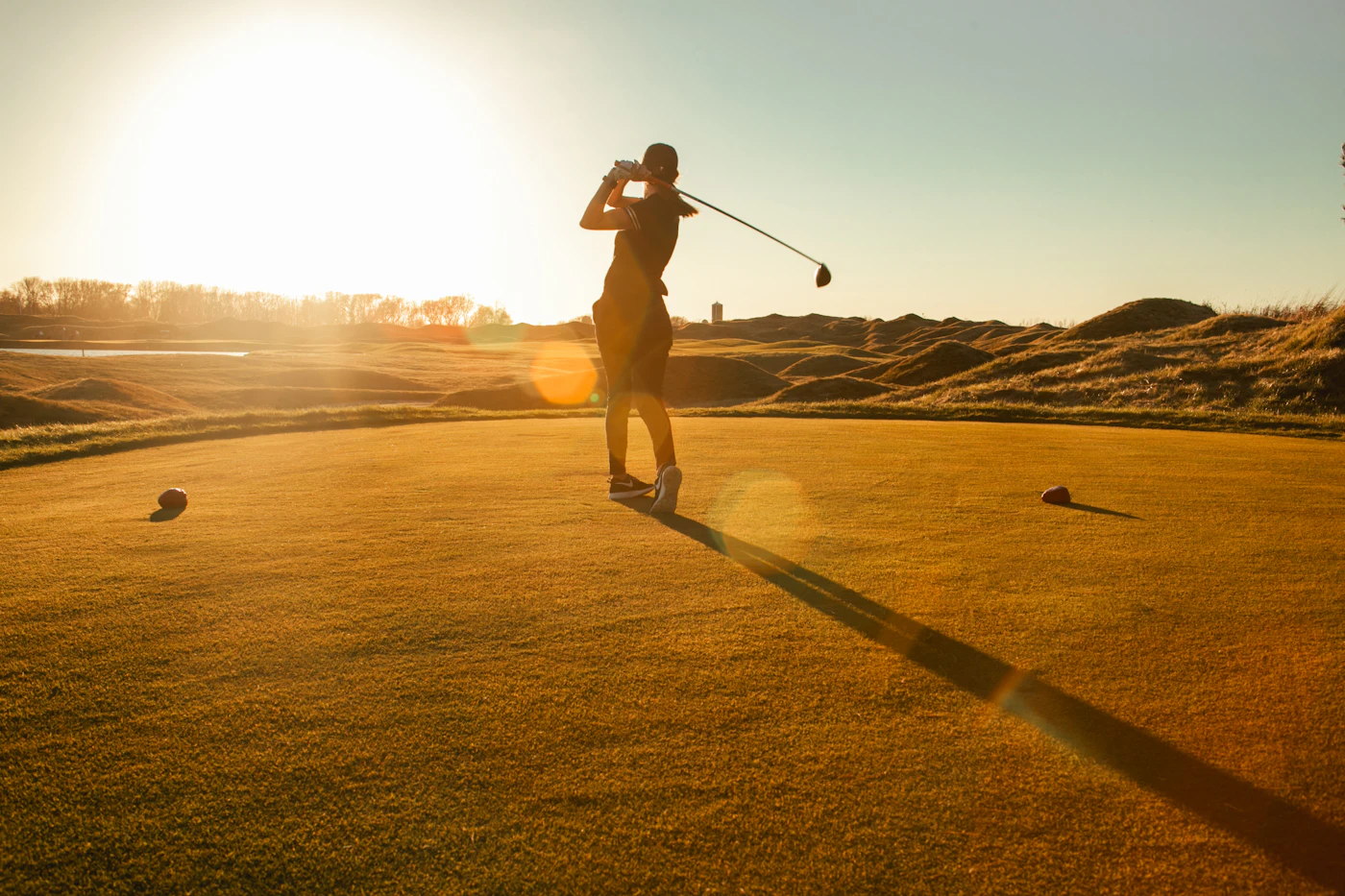 A golfer mid-swing on a sunlit range