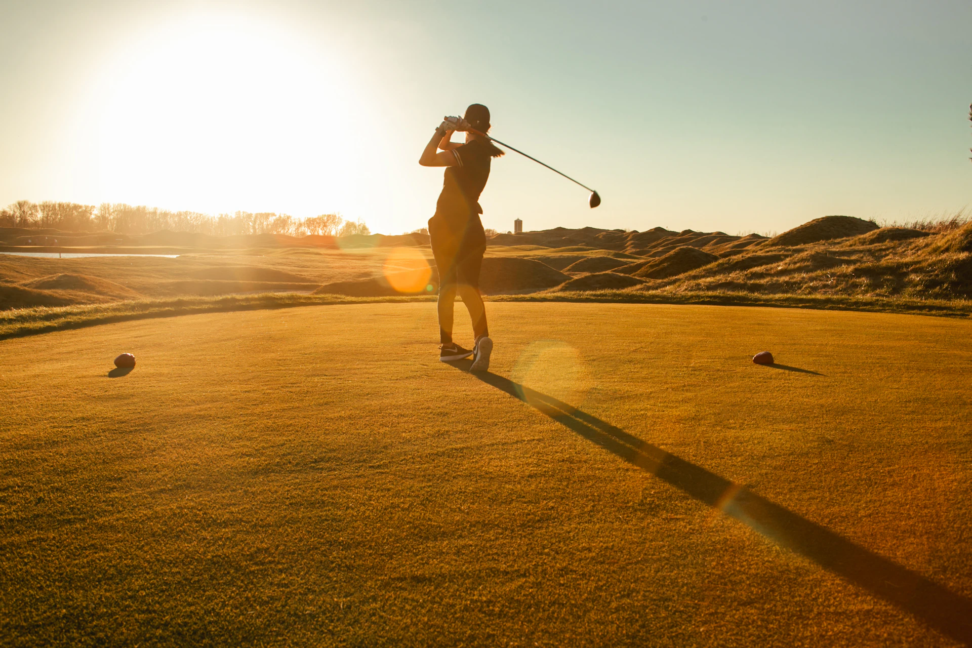 Golfer swinging a driver at sunset