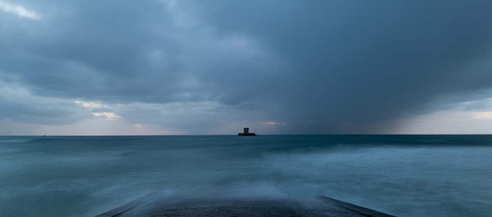 a boat in the ocean under a cloudy sky