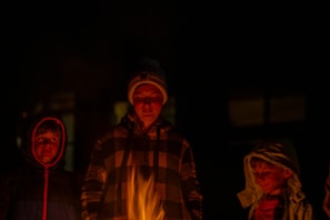 Children gathered around a campfire, crafting stone tools with focused expressions