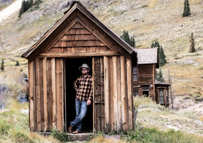 Man wearing a plaid country shirt standing in a sunlit barn with hay bales