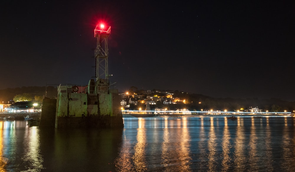 a red light on top of a tower in the middle of a body of water