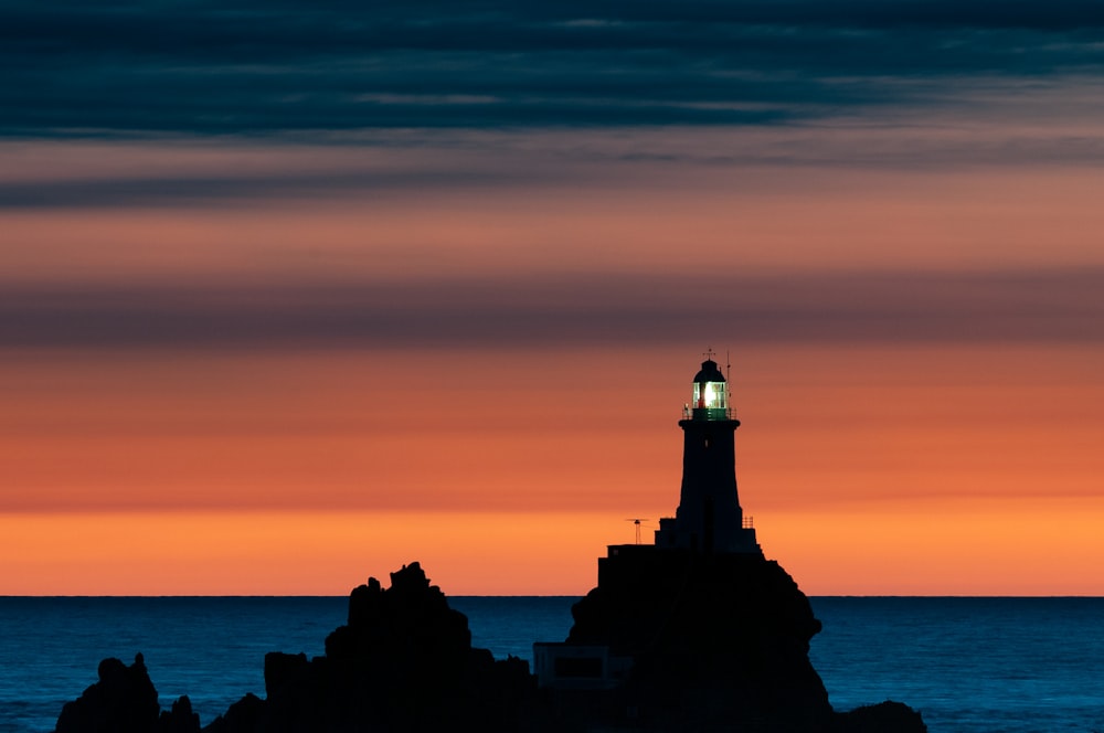 a lighthouse on a rocky outcropping at sunset