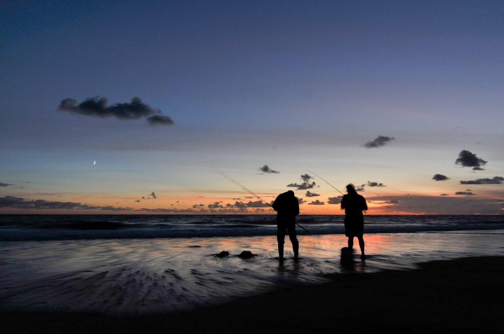 um casal de pessoas em pé em cima de uma praia