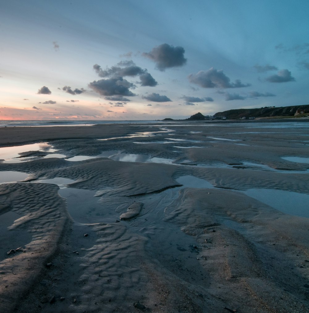 a sandy beach covered in water under a cloudy sky