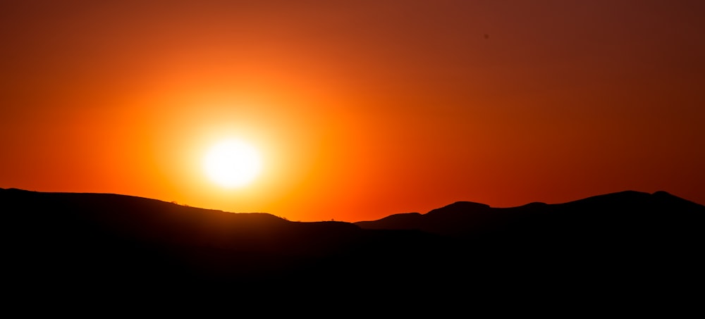 the sun is setting over a mountain range