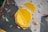 An indoor climbing wall featuring an arrangement of colorful holds and geometric shapes. Dominant yellow panels with various smaller holds in colors such as red, blue, green, and brown are scattered across the textured surface.