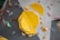 An indoor climbing wall featuring an arrangement of colorful holds and geometric shapes. Dominant yellow panels with various smaller holds in colors such as red, blue, green, and brown are scattered across the textured surface.