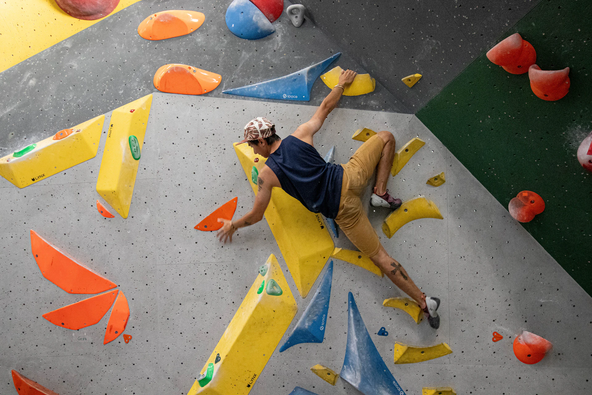 A climber mid-move on a colorful indoor bouldering wall