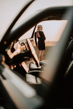 A friendly female chauffeur opening the car door with a warm smile in soft morning light.