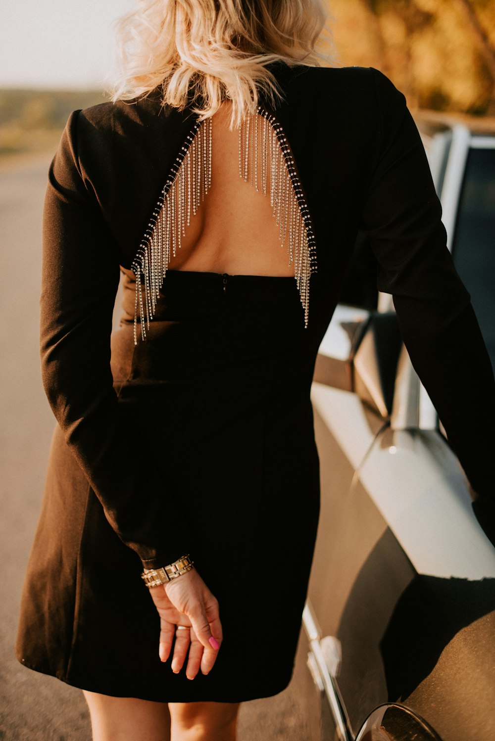 the back of a woman's black dress with fringe detailing