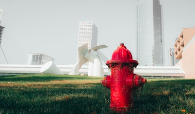 Close-up of a bright red fire hydrant with a cityscape background.