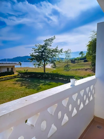 A smiling guest enjoying a morning coffee on a charming balcony overlooking green fields.